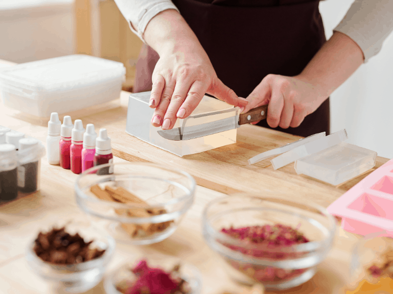 Preparation of ingredients for soap making. Hands of a craftswoman cutting handmade soap. 
Here are top-selling product ideas to try in your home based business or side hustle. Great ideas you can make and sell at home with ideal products to start your small business.