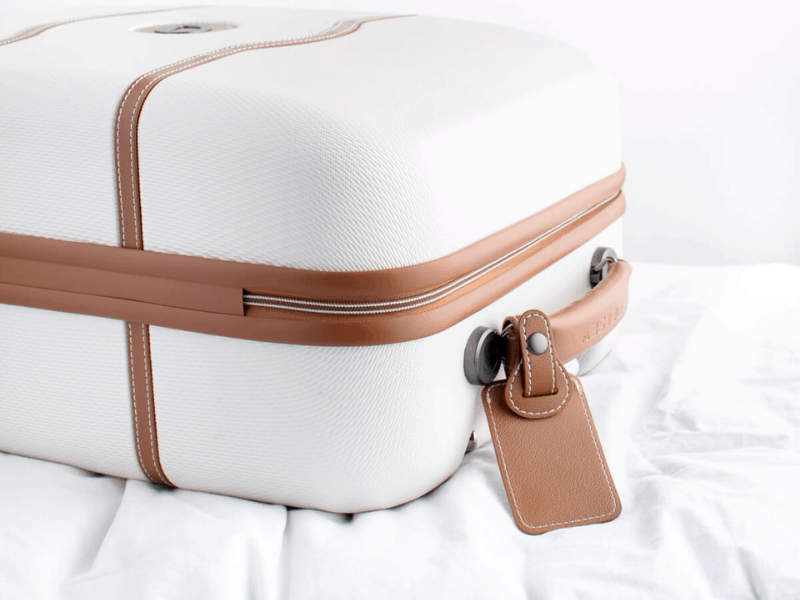 White and brown suitcase, closed, on a white, packing for moving,  bed.Social-Squares_Styled-Stock-Photos-for-Social-Media_0096-1.jpeg