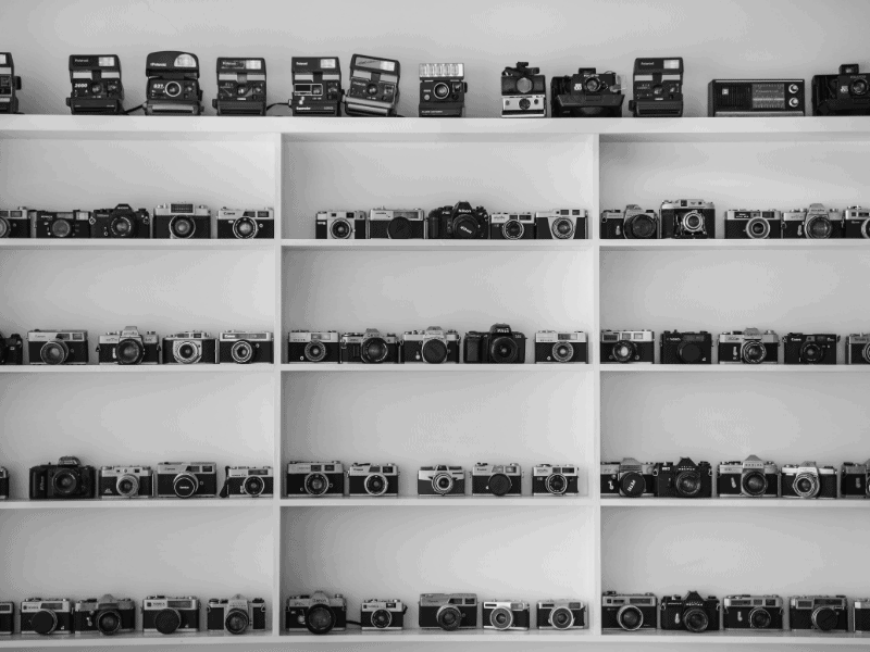 collection of DSLR cameras on white shelves